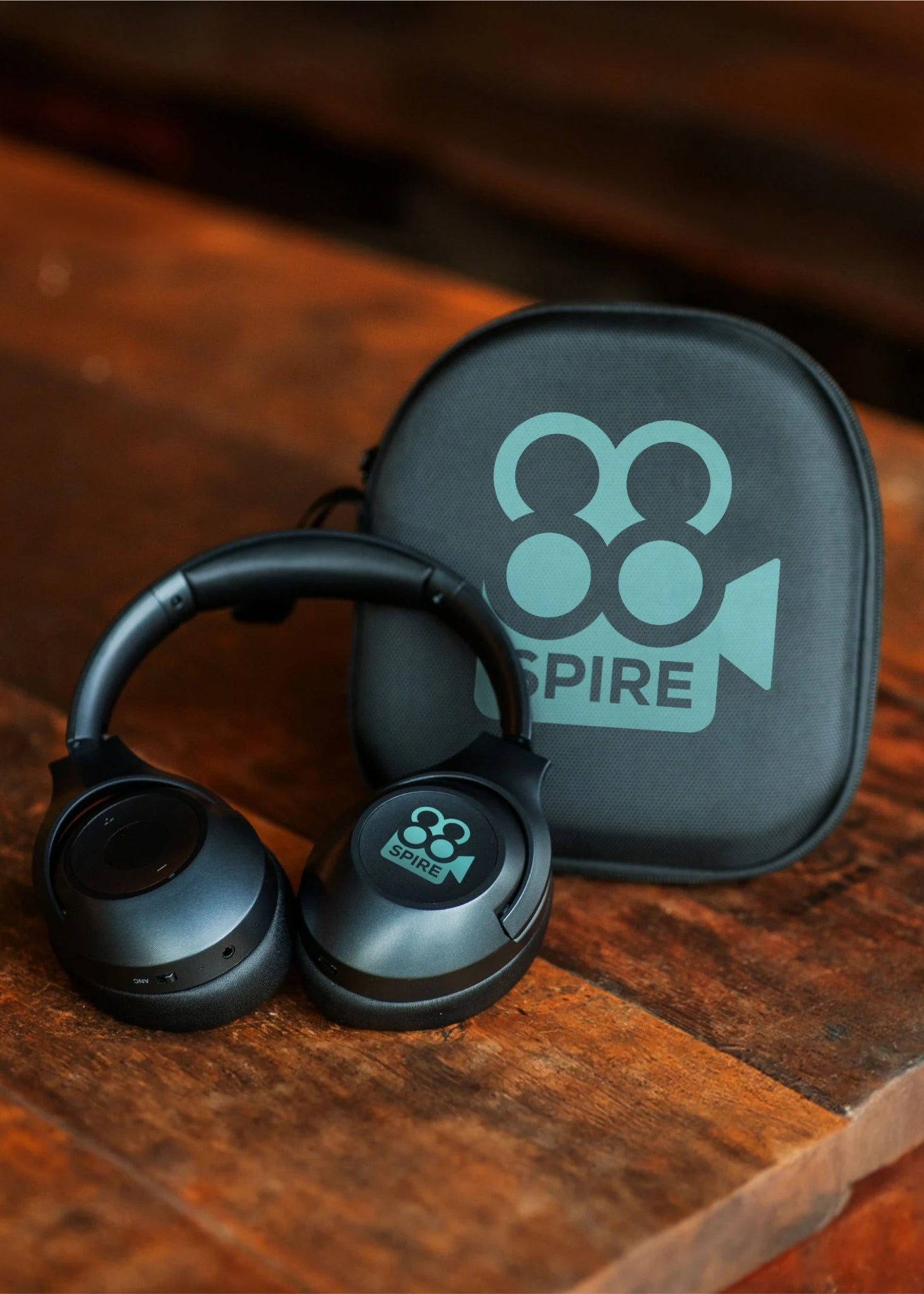 Black headphones with a carrying case on a wooden surface, featuring the 'SPIRE' brand.